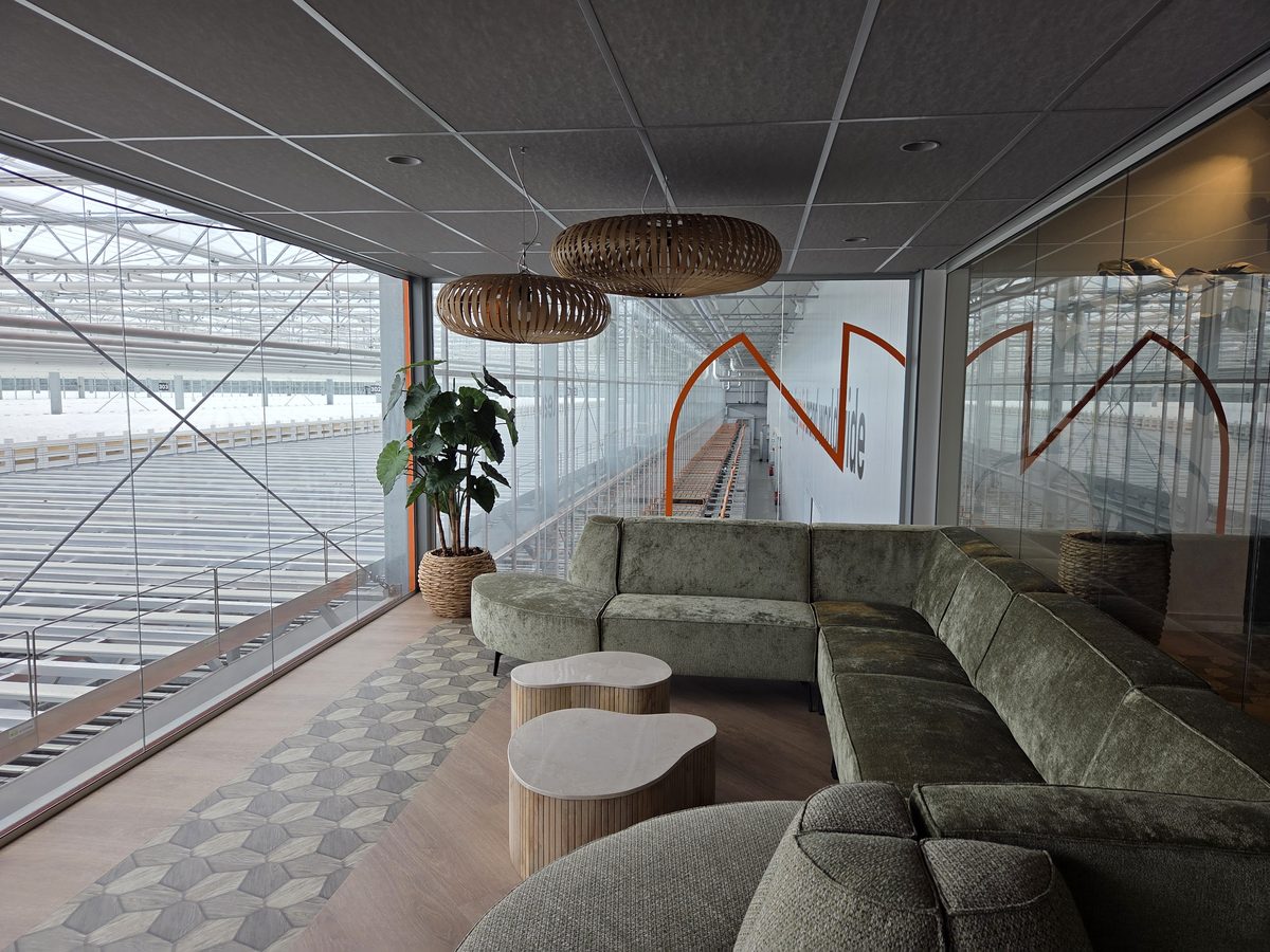Glazen wand langs een lounge met uitzicht over een kas