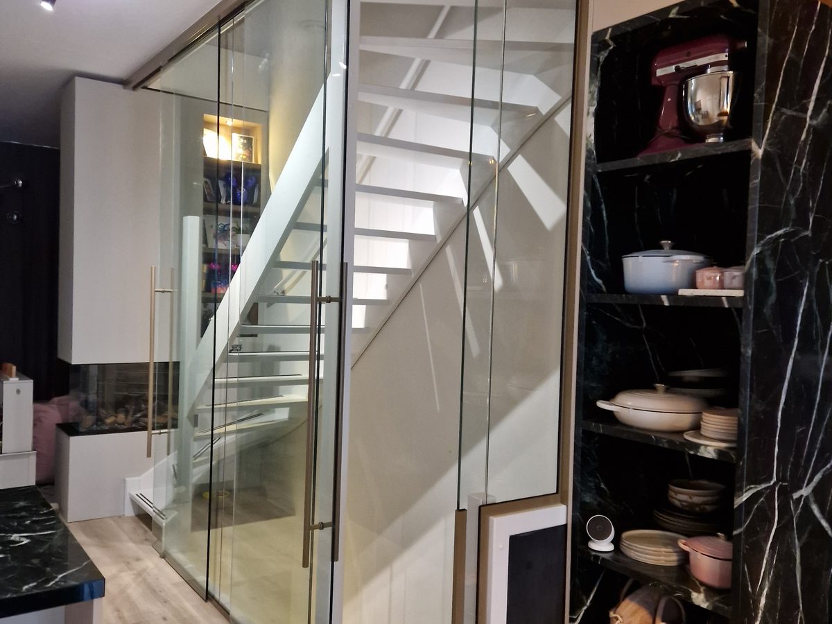 Glazen wand met deur om een trap in een woning