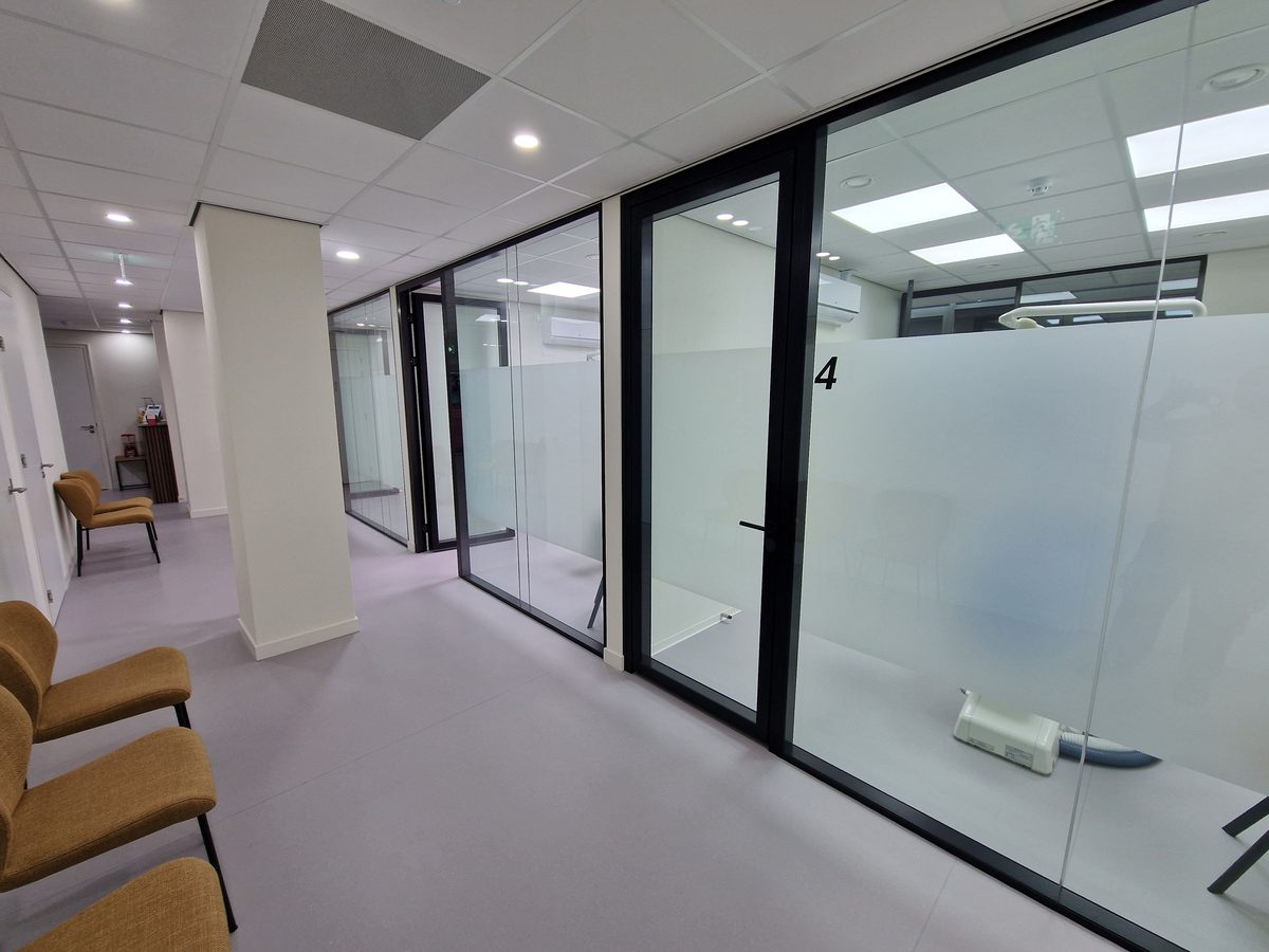 Glazen wand en deur naast de wachtkamer van een tandartspraktijk
