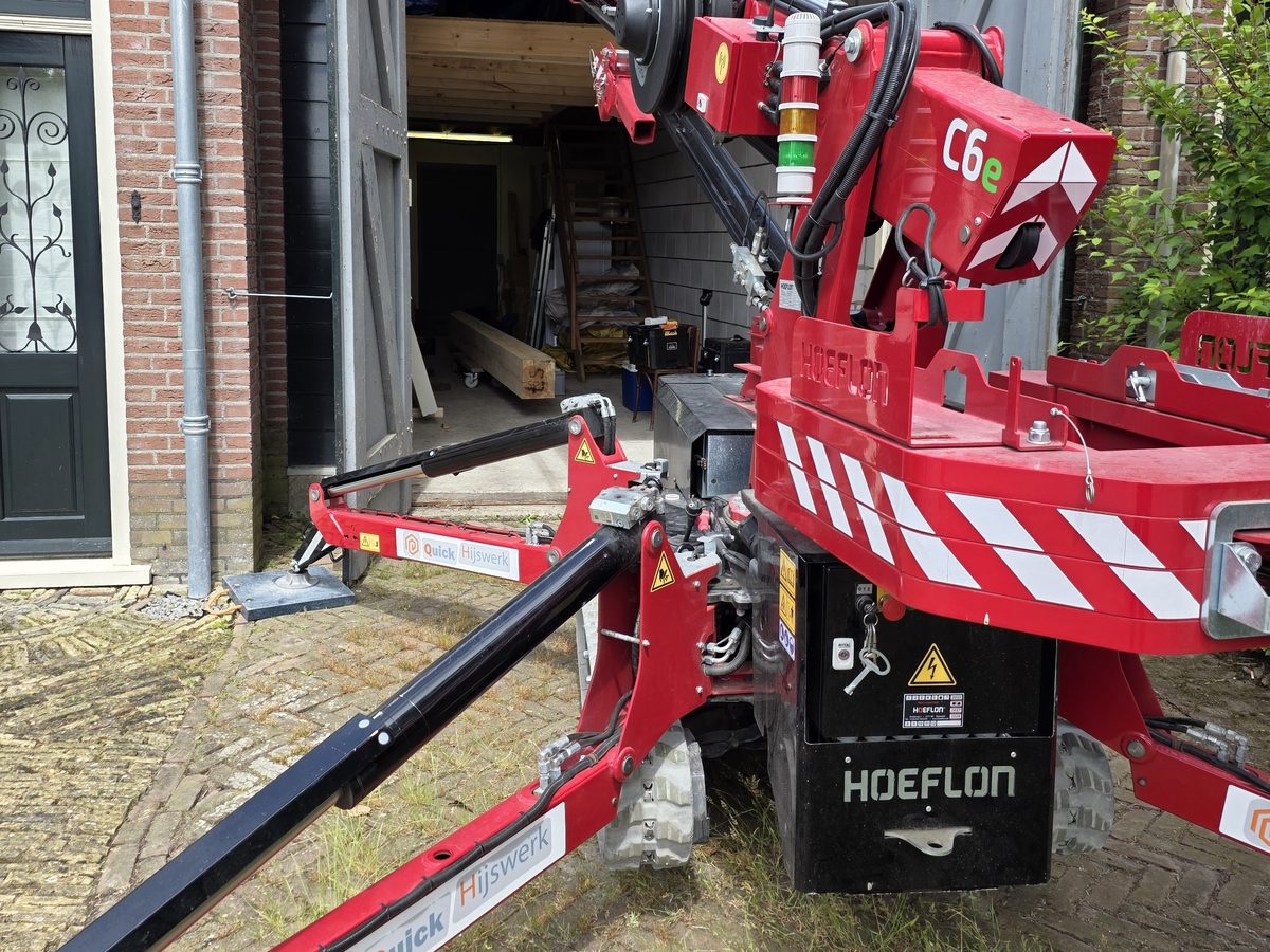 Minikraan zet een houten draagbalk binnen op zijn plek