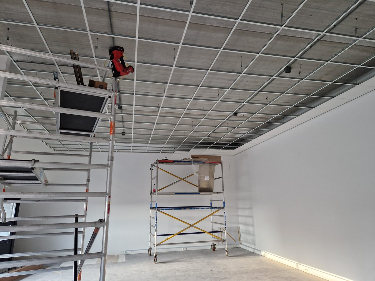 Raster van een systeemplafond tijdens de montage, met rolsteigers