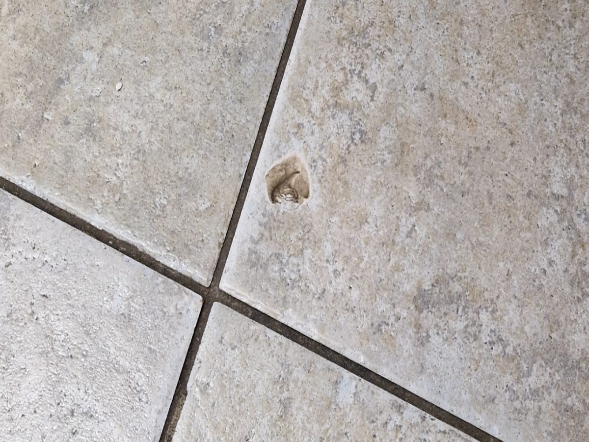 Tegelvloer met een uitgebroken stuk, voor het herstel